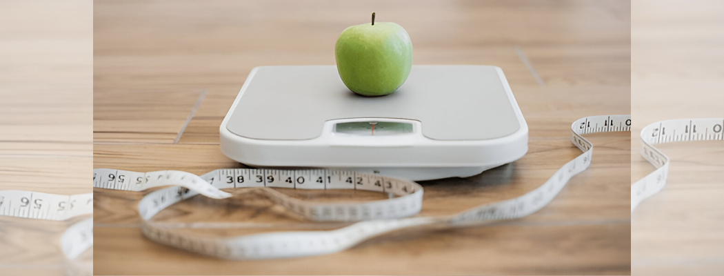 A green apple on a weighing scale with measuring tape in foreground