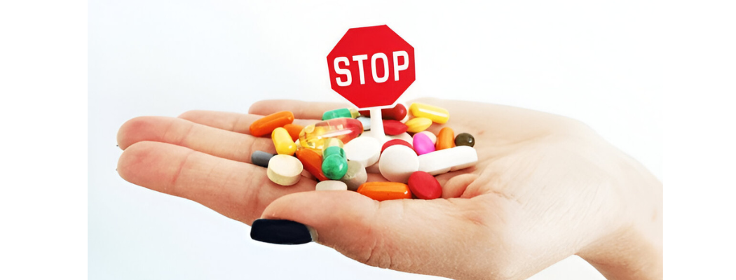 Colorful pills on a hand with a red stop sign on top