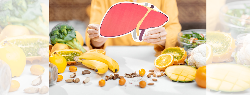 Person holding human liver model surrounded by healthy foods