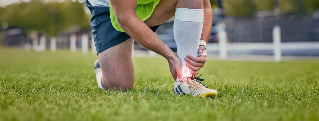 Athlete holding a painful ankle during outdoor training