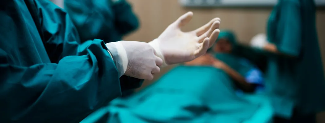 Surgeon putting on sterile glove in operating room