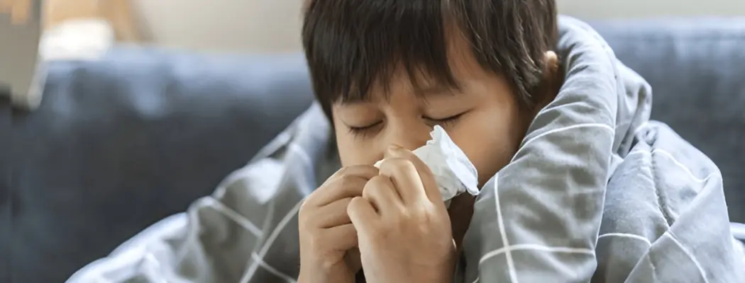 Boy sneezing into tissue